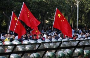 Protesters wave Chinese flags while marching outside Japanese embassy during a protest in Beijing