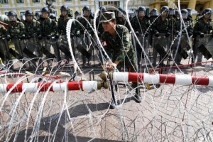 A security personnel adjusts razor wire as anti-government protesters arrive to the Defense Ministry in central Bangkok