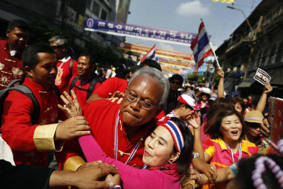 Protest leader Suthep Thaugsuban is hugged by anti-government protester during march through Chinatown in Bangkok