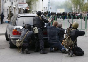 Pro-Russian armed men take cover behind a car near the local police headquarters in Luhansk