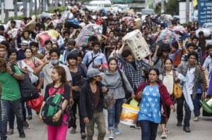 Cambodian migrant workers carry belongings as they walk to cross border at Aranyaprathet in Sa Kaew