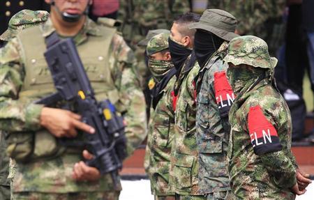 Defected members (with armbands) of Colombian guerrilla group ELN fall in at a military base during their surrender and the handover of their weapons, in Cali July 16, 2013.