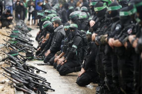 Palestinian members of al-Qassam Brigades, the armed wing of the Hamas movement, pray before a military parade in Gaza City