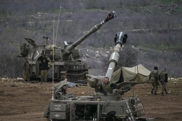 Israeli soldiers are seen next to mobile artillery units near the border with Syria in the Golan Heights