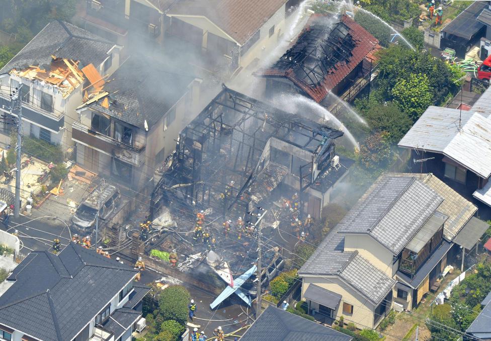 An aerial view shows debris of a crashed light plane and burning houses are seen after the plane went down in a residential area and burst into flames, in Chofu, outskirt of Tokyo