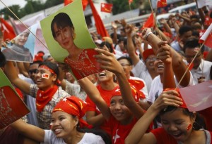 Supporters of the NLD party cheer as they watch increasing votes on a screen at the roof of the NLD office in Yangon