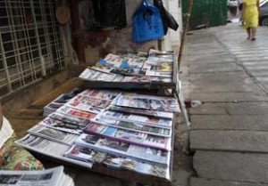A woman arranges newspapers to sell by the street side in Yangon